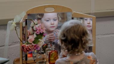 Little girl looking in dressing table mirror
