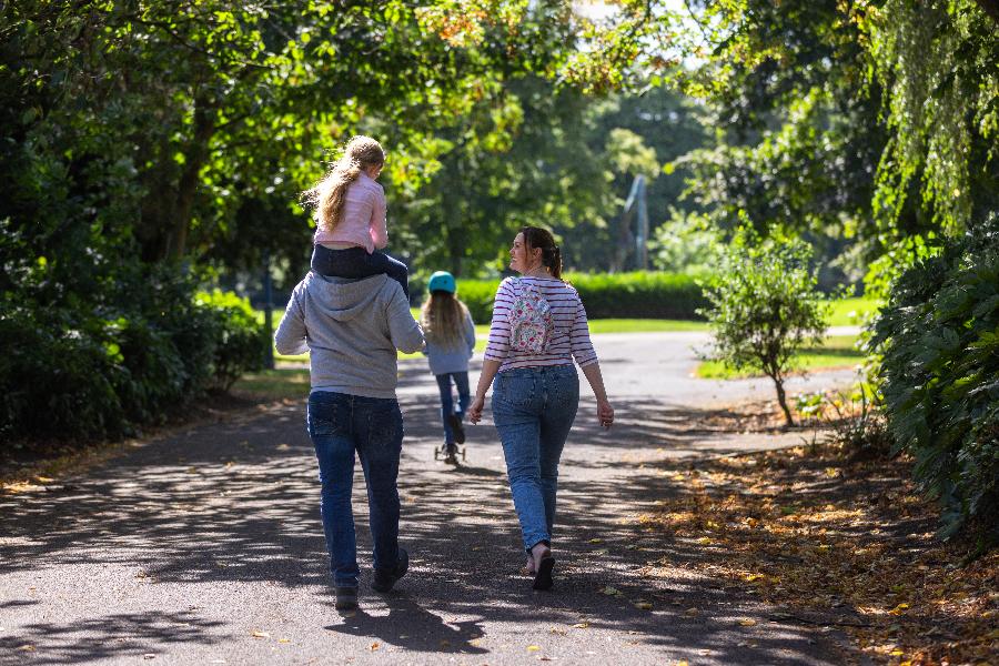 Family walking away with young girl on the shoulders of a man